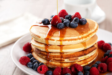 Pancakes with berries and maple syrup on a plate.