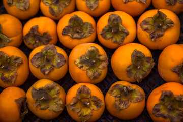 Colorful and fresh persimmons aligned on an  table