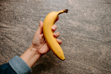 mano de chica joven sujetando un plátano en cocina con fondo aislado