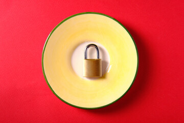 Metal padlock on a plate, on a red background, a symbol of diet