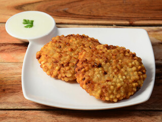 Sabudana vada or Sago fried cake served with chutney, popular fasting recipe from India. isolated over a rustic wooden background, selective focus
