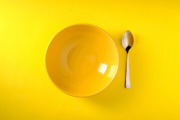 Yellow plate on yellow background, top view