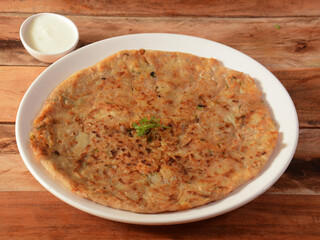 Aloo Paratha or Indian Potato stuffed Flatbread. Served with fresh curd. isolated over a rustic wooden background, selective focus