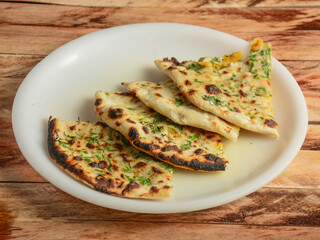 Aloo Paratha or Indian Potato stuffed Flatbread.. isolated over a rustic wooden background, selective focus