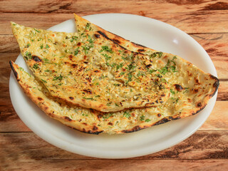 Butter garlic naan, isolated over a rustic wooden background, selective focus
