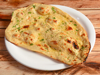 Butter naan, isolated over a rustic wooden background, selective focus