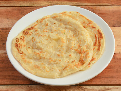 Kerala Paratha, a layered flat bread using wheat flour, popular dish in south India. isolated over a rustic wooden background, selective focus