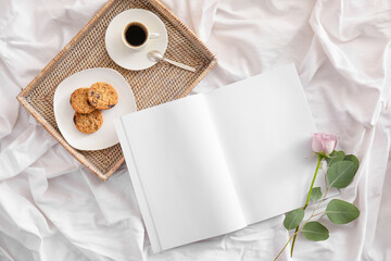 Blank magazine, tray with breakfast and flower on bed