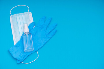 Fototapeta na wymiar Popular medical antiviral mask, syringe with virus vaccine and antiseptic sanitizer on a blue background. A set of essential items during a viral pandemic