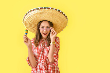 Beautiful young woman in sombrero hat and with maracas on color background