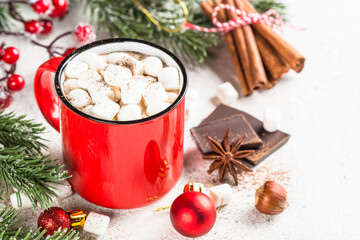 Christmas drink. Hot chocolate with marshmallow in red mug and christmas decorations at white table.