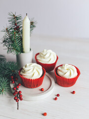 Tasty cupcakes decorated with spruce branches and red berries on a white background. Sweets for the...