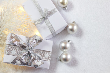 Christmas background with gifts, baubles and twigs in silver and white
