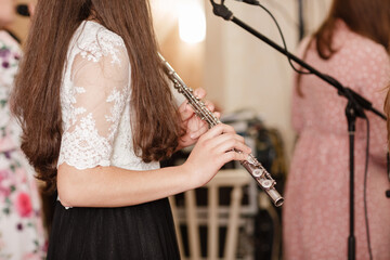 Flutist, young girl playing the flute, hands, fingers on keys closeup, children playing transverse side blow flute, detail shot, classical music, wind instrument performance player up close abstract