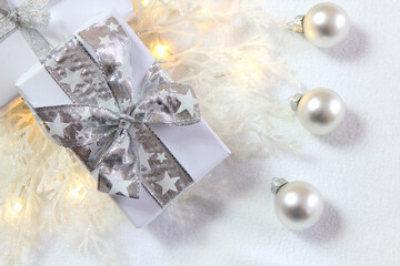 Fototapeta na wymiar Bożonarodzeniowa srebrno-biała dekoracja z prezentami, bombkami i oszronionymi gałązkami 