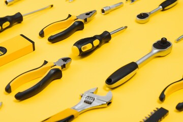 Tools top view on yellow background. Plier, open wrenches, screwdrivers and staple gun flat lay with copy space.