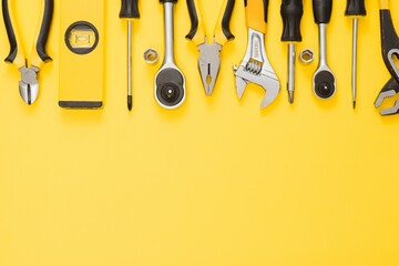 Yellow and black handy tools (pilers and screwdriver) isolated on yellow background