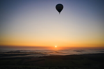 Fototapeta na wymiar Silhouette of a hot air balloon on a background of blue sky at sunrise with fog