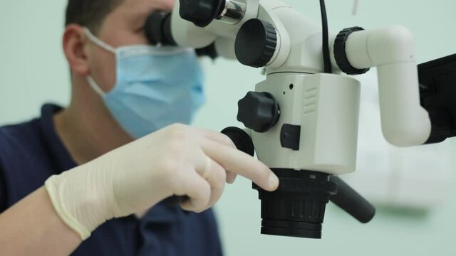 Dentist is treating patient in modern dental office. Doctor making teeth examination research survey using microscope in dentistry.
