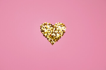 shiny golden heart made of sequins on a pink background. valentine's day