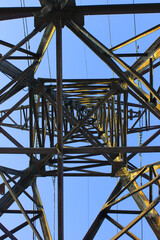 High voltage transmission tower line against blue sky, bottom view. iron construction.