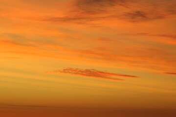 Sun below the horizon and clouds in the fiery dramatic orange sky at sunset or dawn backlit by the sun. Place for text and design