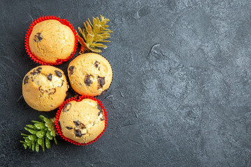 Horizontal view of four delicious cupcakes and new year decorations on dark background