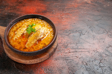 bottom view chicken soup in wooden bowl on chopping board on dark red background with free space