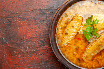 top half view chicken soup in wooden bowl with handle on dark red background with free space