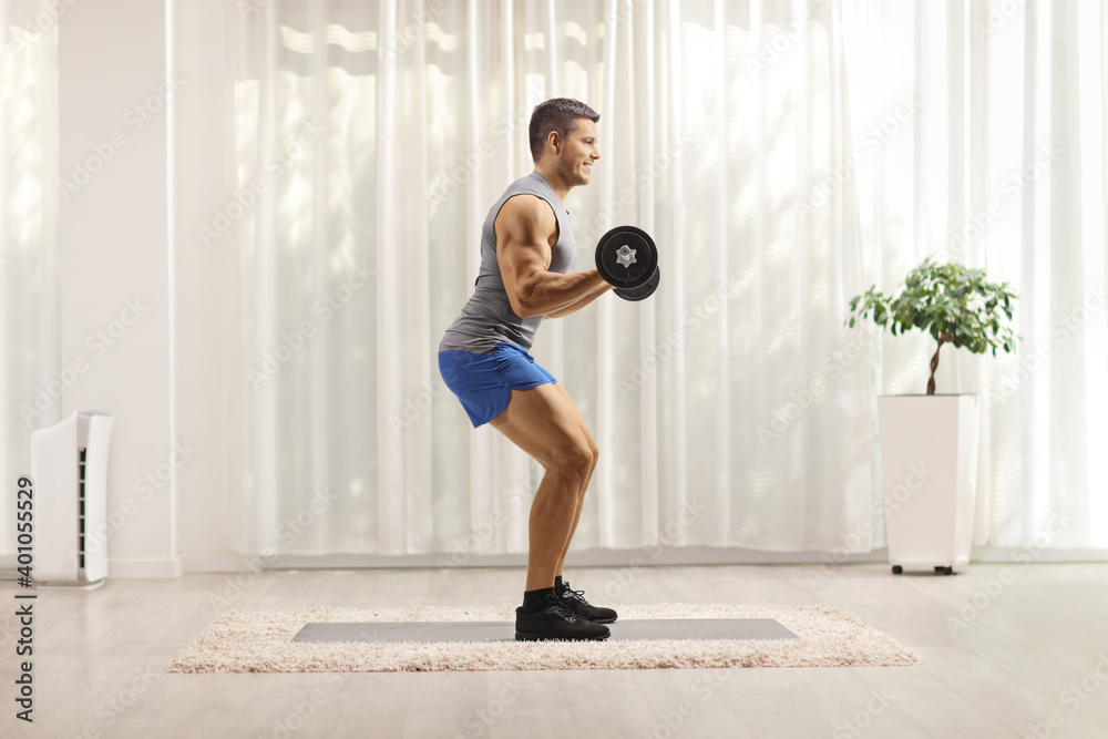 Canvas Prints Young man bodybuilder lifting weights at home