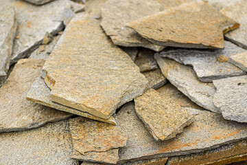 Stone natural flagstone piled in a pile. Natural stone flagstone, laid in uneven rows. Background .