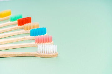 A set of Eco-friendly antibacterial toothbrushes made of bamboo wood on a light green background. Environmental care trends