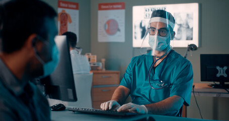 Male patient in mask speaking with doctor