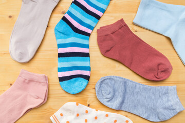 multicolored new socks in different sizes stacked on a wooden background. clothes for women