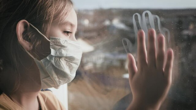 Little girl in a protective mask sits in quarantine at home. Stay at home, stay safe. Protection against virus and infection. Concept of coronavirus quarantine or covid-19.