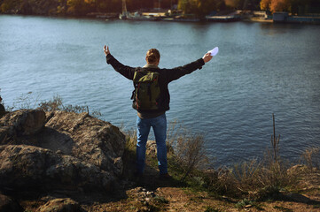 Young man rise hands on beautiful lake and mountain Landscape. Man standing on mountain with open arms and enjoying the beautiful autumn scenery.
