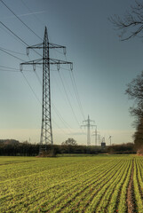 Hochspannungsleitung auf dem Feld. Stromtrasse zu Horizont.