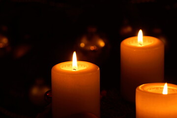 Close up of glowing candles spending warn golden light in front of a christmas tree