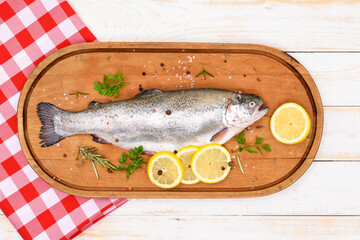 Raw rainbow trout marinated in fresh herbs and prepared for cooking on a wooden vintage cutting board