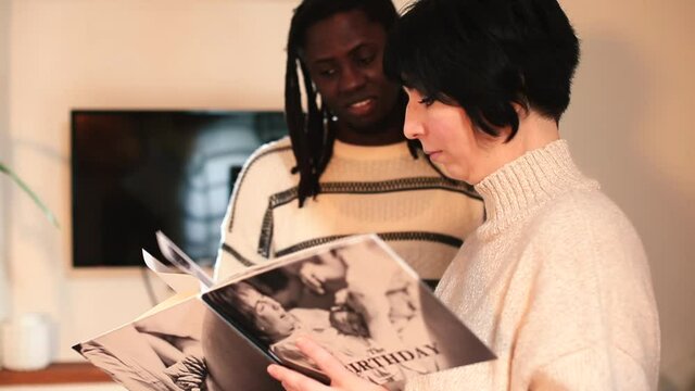 A woman is discussing a photobook about childbirth with an Afro man. Consultation with a doula specialist regarding childbirth. Preparing a young father.