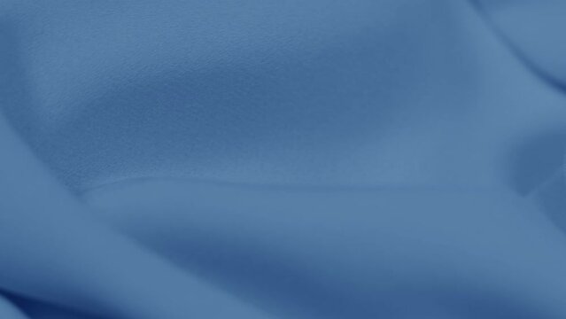 Closeup view 4k video of smooth wavy pastel blue cloth rotating fast. Real viscose or polyester synthetic fabric texture.