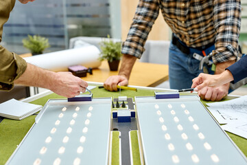 close-up of modern building design on table in office, creative constructive projection at work. engineers work on planning and 3d architecture model, discussing. design and graphics concept