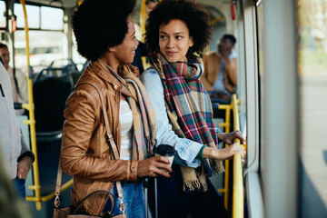 Obraz na płótnie Canvas Happy black women talking while traveling by bus together.