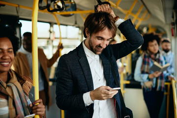 Happy entrepreneur using smart phone while traveling to work by bus.