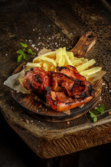 Grill house concept. Grilled, roasted, fried tasty pork meat with french fries on the old wooden cutting board.