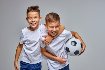 kid boys go in for soccer sport professionally, stand hugging each other, have fun, smile at...