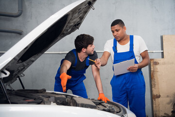Mechanics inspect the engine of a automobile and discuss repair