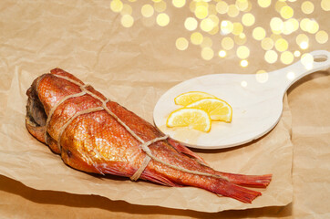 Hot smoked sea bass tied with a rope, with lemon, close-up on the background of crumpled paper....