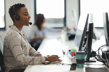 Businesswoman with headset working at computer in call center office