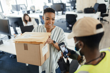 Businesswoman receiving packages from delivery man with smart phone